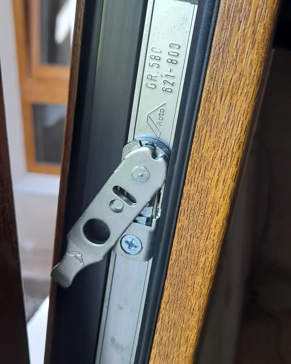 El herraje Roto de una ventana de PVC color roble, de cerca, con la marca grabada
