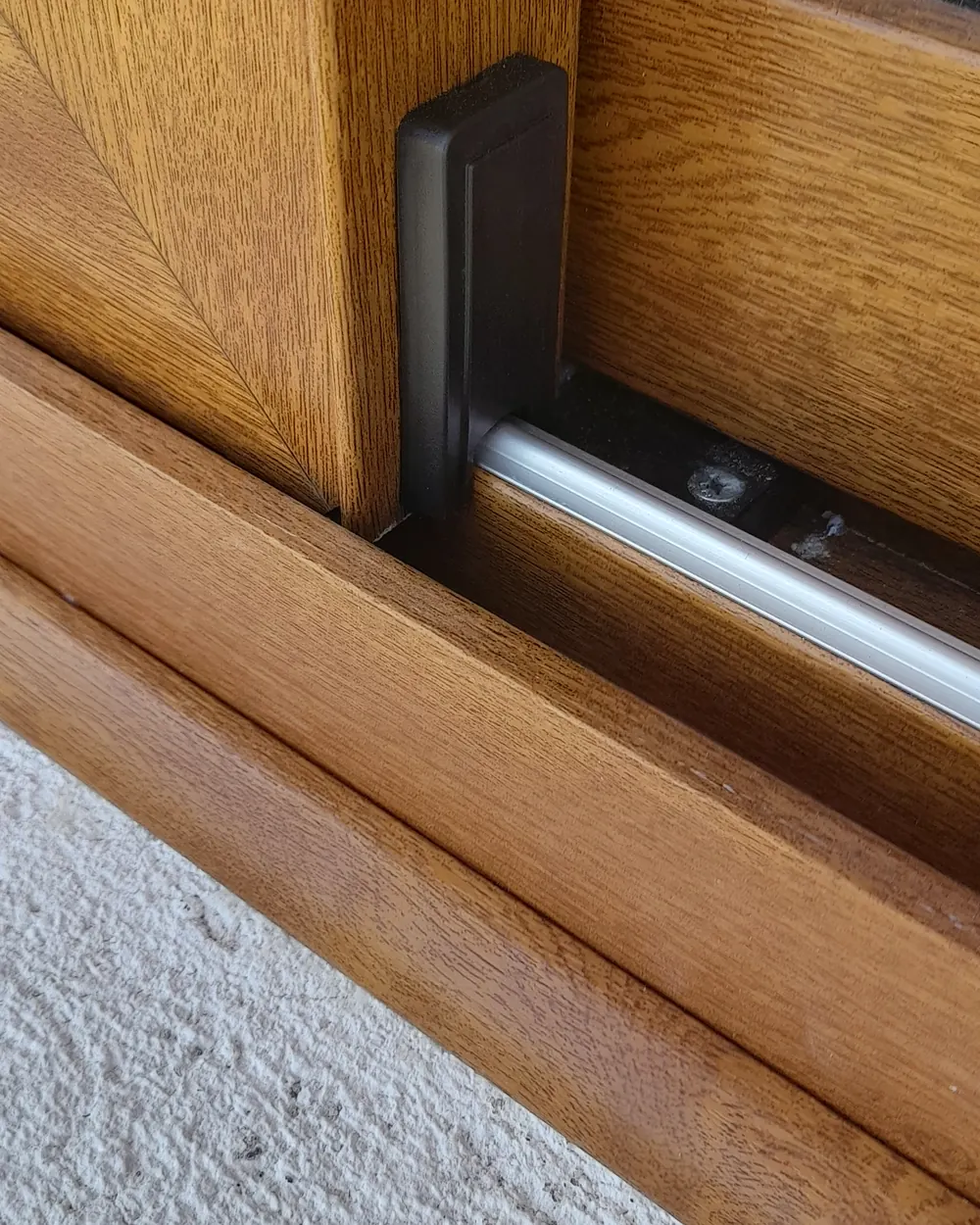 Hoja de una ventana de PVC con folio símil roble y su manija, de cerca