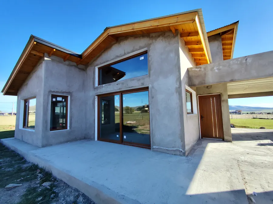 Casa en obra con ventanales de PVC roble dorado y las sierras atrás