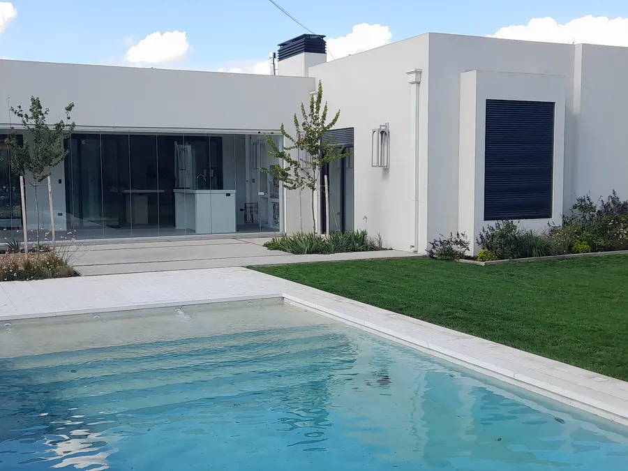 Casa blanca con pileta y ventanales de perfil negro