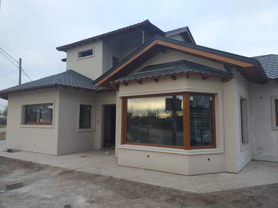 Casa con bow window y ventanas de PVC roble dorado