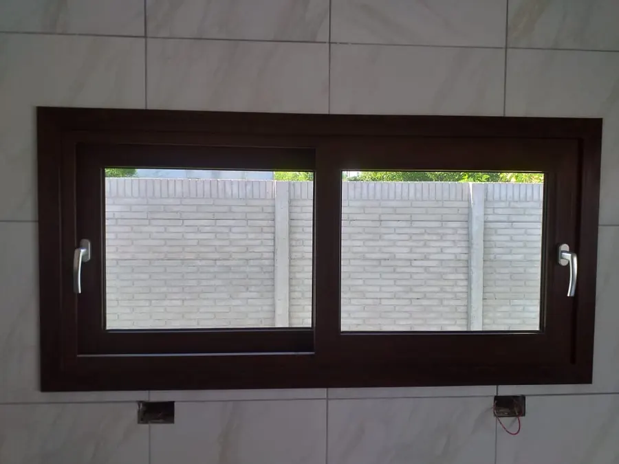 Ventana corrediza de perfil marrón en una cocina con azulejos