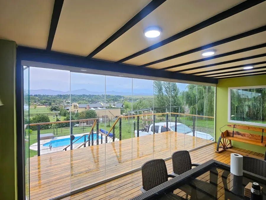 Cerramiento de vidrio templado sobre un deck de madera, con la pileta abajo