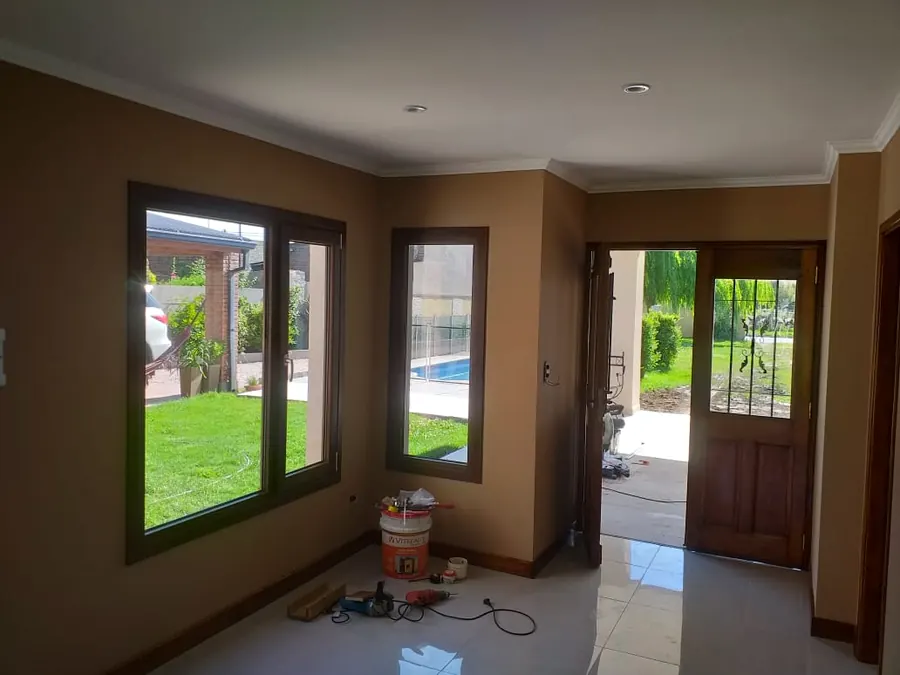 Living con ventanas y puerta de perfil marrón, la pileta afuera