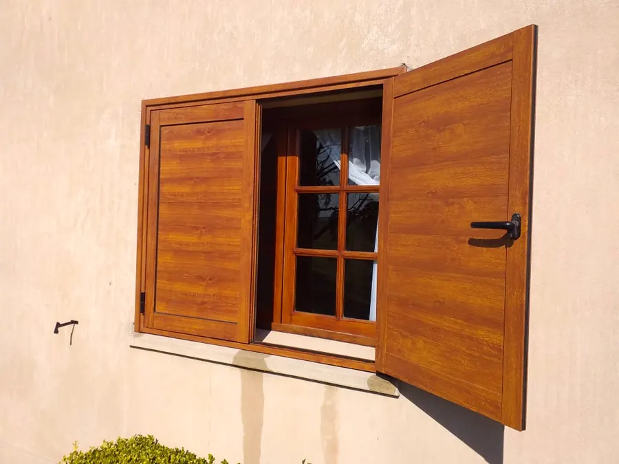 Ventana con postigos de PVC símil roble, abiertos