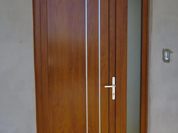 Puerta de PVC roble dorado con líneas verticales y paño lateral