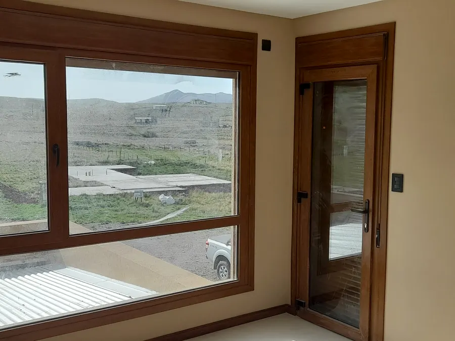 Ventana y puerta balcón de PVC roble dorado, con las sierras de fondo
