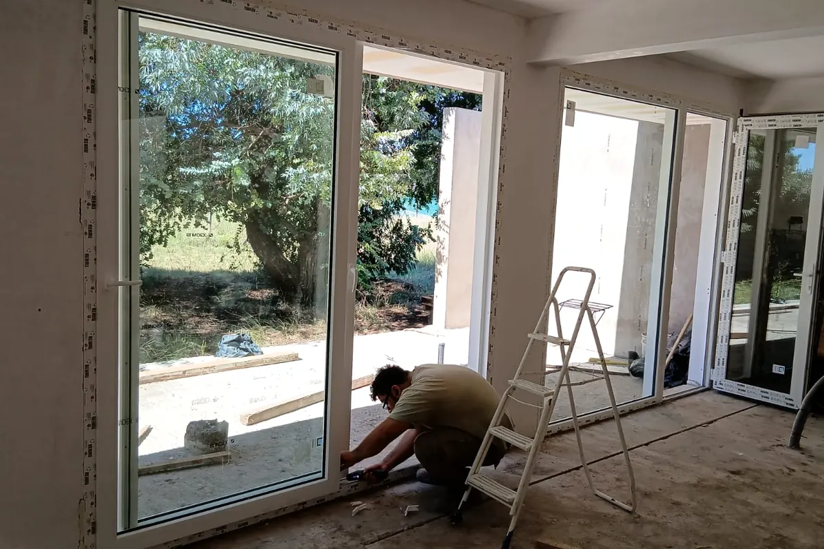 Un colocador de El Angel ajustando una puerta corrediza de PVC en una obra
