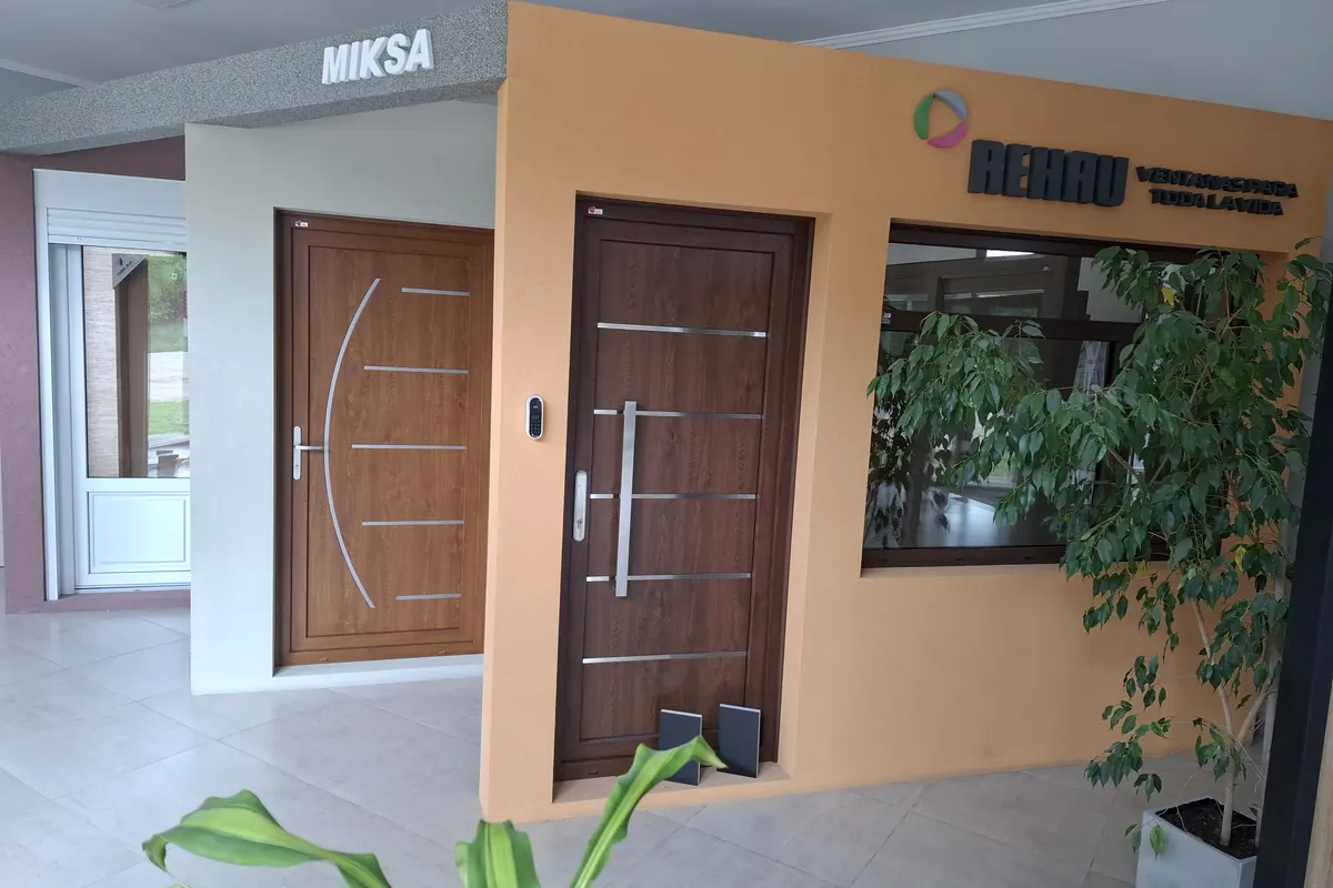 El showroom con puertas de PVC en la pared naranja y el cartel de REHAU